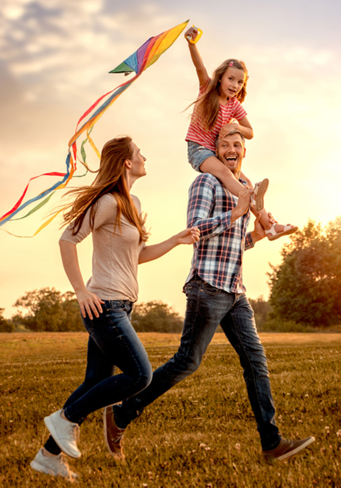 parents with child flying a kite from dad's shoulders